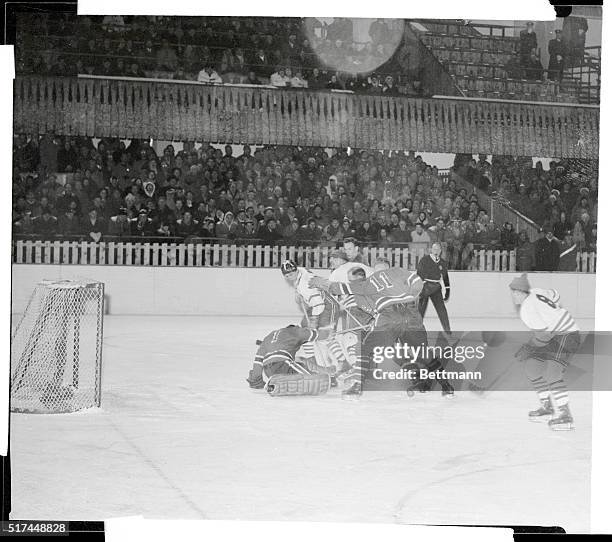 Olympic hockey team goalie Willard Ikola out a Canadian goal attempt during the second period of their game at Cortina, January 31. Also in action...