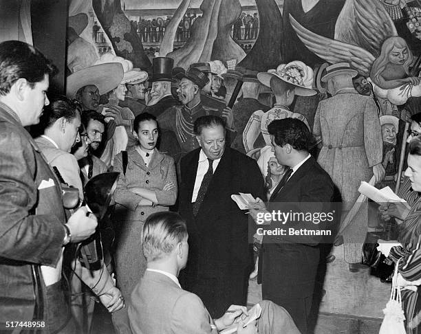 Famous Mexican painter, Diego Rivera is surrounded by newsmen during interview as he points to a self portrait in front of the famous mural in the...