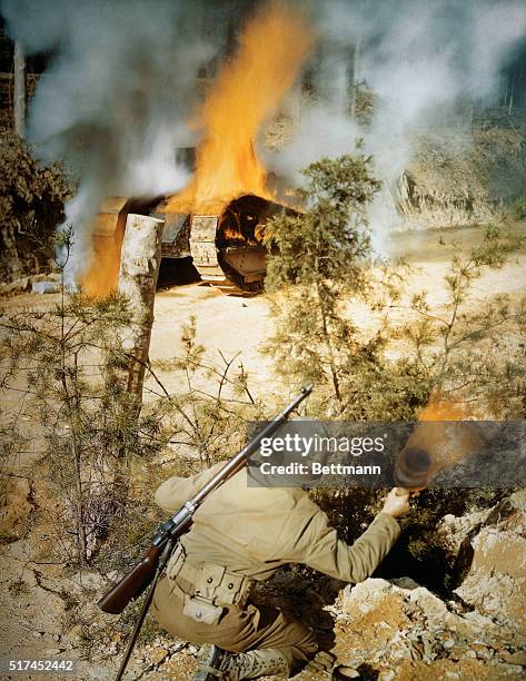 This is a U. S. Army soldier preparing to throw another Molotov cocktail at tank, which is already on fire.