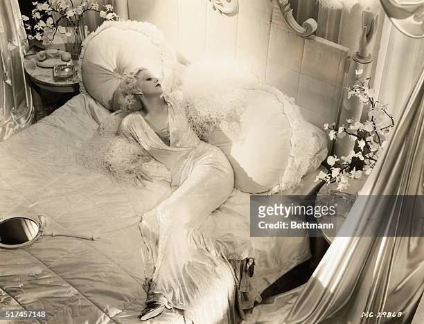 Jean Harlow , American actress known as the sex symbol of the 1930s, shown lounging on a bed in this publicity photo.