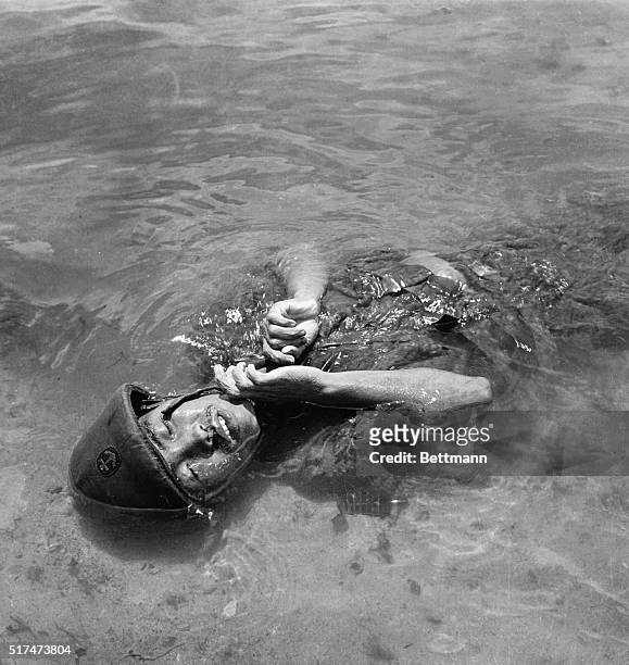 Still wearing his helmet, the body of a Jap soldier floats in the water at Tanapag Harbor, Saipan, after participating in a futile counter-attack...