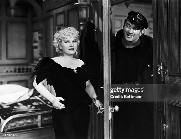 Mae West answers the door for Victor McLagen in the motion picture Klondike Annie.