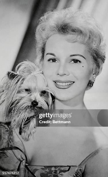 Eva Gabor, sister of the better-known Zsa Zsa, but an actress in her own right, fondle's her tiny Yorkshire terrier "Sunny Boy", during an interview...