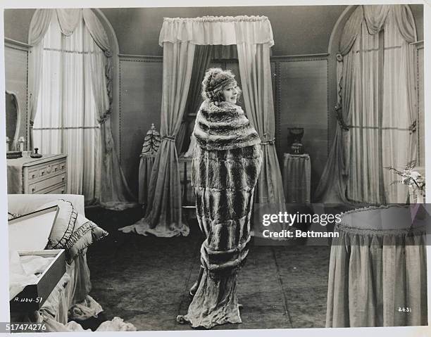 Flapper modeling fur wrap, coat and headband in bedroom.