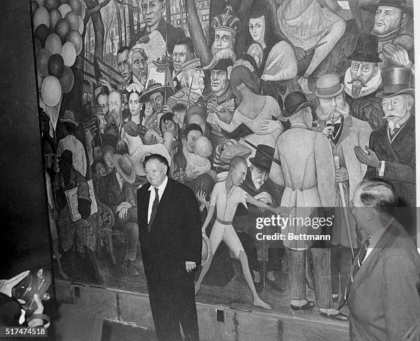 Famous Mexican painter, Diego Rivera is surrounded by newsmen during interview as he points to a self portrait in front of the famous mural in the...