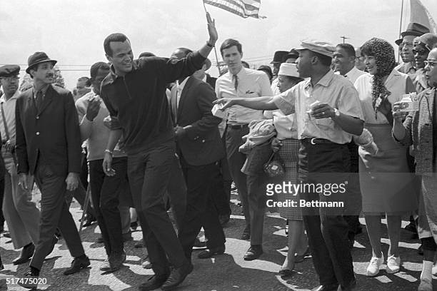 Montgomery, AL-ORIGINAL CAPTION READS: Singer Harry Belafonte waves to Dr. Martin Luther King, Jr. As he leaves the column of civil rights marchers...