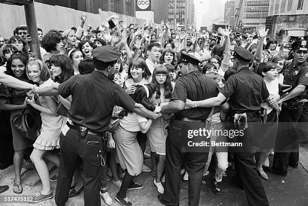 New York, NY- New York City policemen try to restrain hordes of teenagers- mostly of the female variety -from crashing into the Warwick Hotel, the...