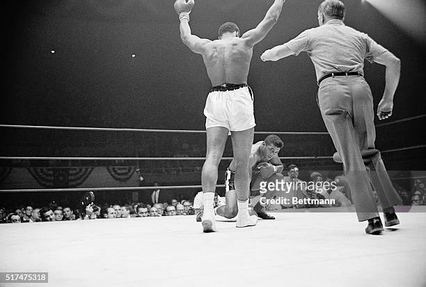 Champion Cassius Clay, arms raised, is waived to a neutral corner as challenger Floyd Patterson takes a mandatory count of eight, November 22, during...