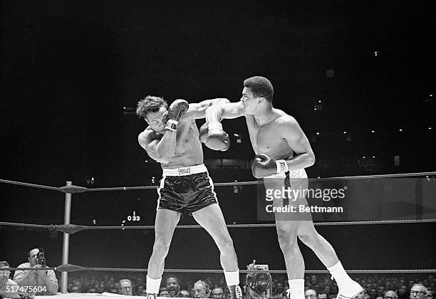 Challenger Cleveland Williams takes refuge behind a glove as champion Cassius Clay bores into the attack, in the 1st round here. Clay retained his...