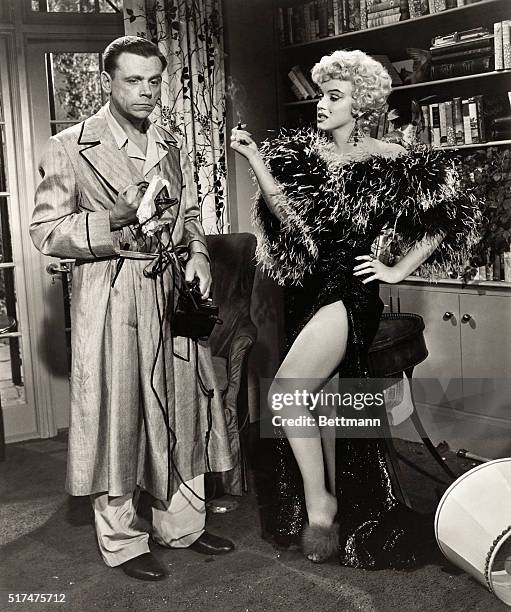 TOM EWELL AND MARILYN MONROE DISCUSS A BAD PHONE CONNECTION IN THE 1955 20TH CENTURY FOX FILM THE SEVEN YEAR ITCH. MOVIE STILL.