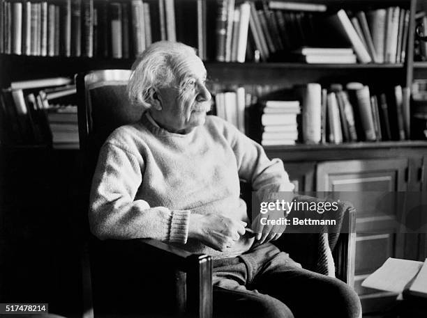 Princeton, New Jersey: Physicist Albert Einstein , seated in book-filled office holding a pipe.