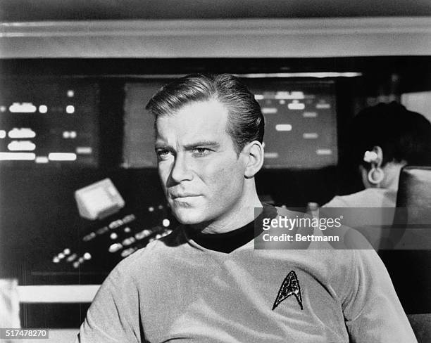 William Shatner as Captain James Kirk with a look of concern in close up of him seated in the Starship Enterprise during an episode of Star Trek.