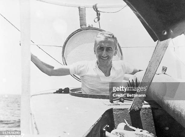 Oceanographer Jacques Cousteau emerges halfway out of submarine hatch.