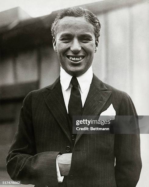 Up close shot of Charles Chaplin , without mustache. He is smiling with his hand in his jacket. He achieved huge success in character of "the tramp",...