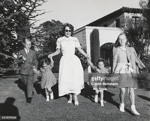 Joan Crawford and four children, Christopher, Cathy, Cynthia, and Christina romp on lawn following party given by Ann Rutherford for daughter...