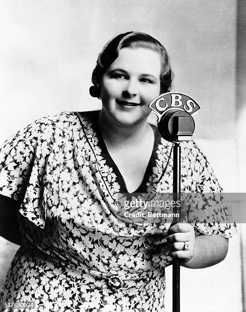 Portrait of Kate Smith , American singer popular on radio during the 1930s and 1940s. Photograph shows her holding CBS microphone.
