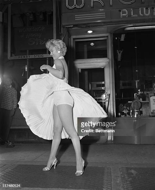 Film star Marilyn Monroe poses over a Manhattan subway grate as the wind blows her white dress up. Photographers capture the moment on camera, which...