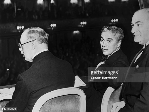 With a questioning expression, Charlie Chaplin, world renowned clown, poses for the photographer, while enjoying the premier of his latest movie...