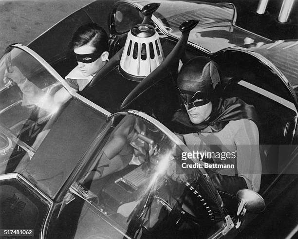 Adam West, and Burt Ward are shown as their television characters, "Batman" and Robin." They are shown in the "Batmobile." This is a still photo from...
