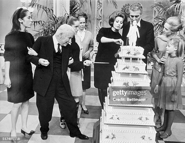 En Garde. Pinewood, Bucks, England: Charlie Chaplin is about to stab his six-tiered birthday cake during a surprise party thrown for him on the set...