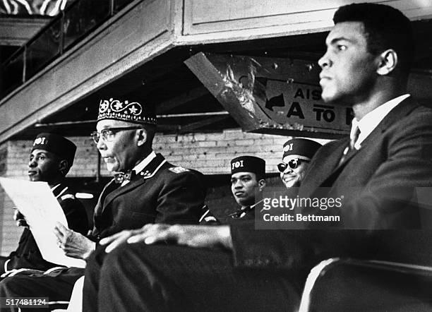 Heavyweight boxing champion Muhammad Ali sits on the podium with Nation of Islam leader Elijah Muhammad while attending the National Meeting of the...