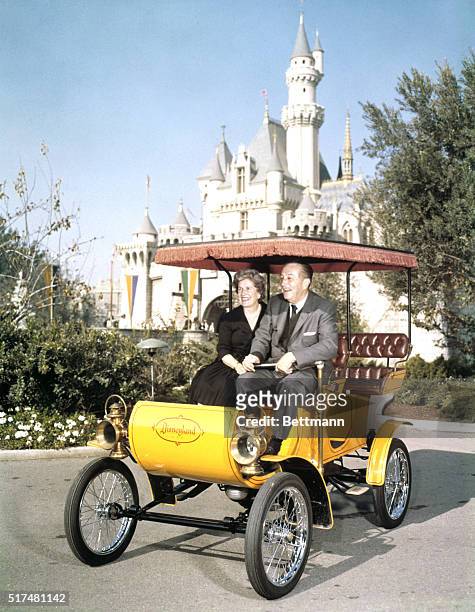 Walt Disney sits with wife in an antique auto at Disneyland.