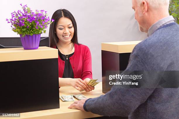 guichetier de banque qui propose des services client au comptoir de banque - bank counters photos et images de collection