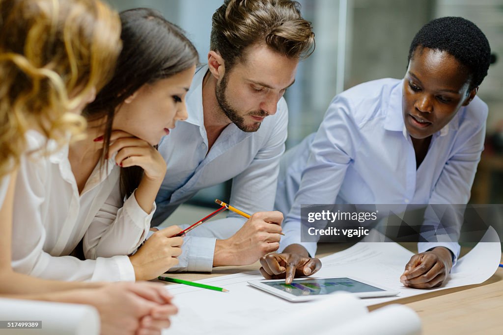 Multiethnic Team of designers reviewing blueprint in the office.