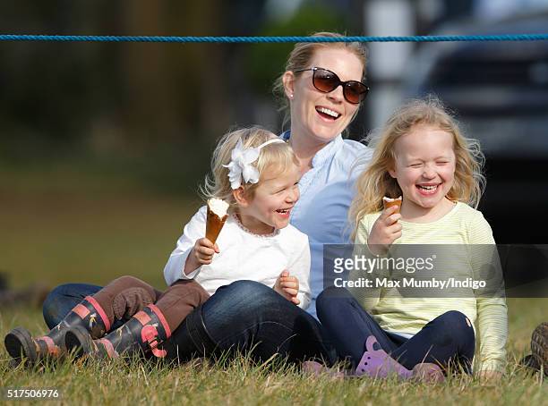 Autumn Phillips and daughters Isla Phillips and Savannah Phillips eat ice creams as they watch the show jumping during the Gatcombe Horse Trails at...