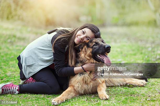 junge frau umarmen ihr deutsch hirte im park - caucasian shepherd dog stock-fotos und bilder