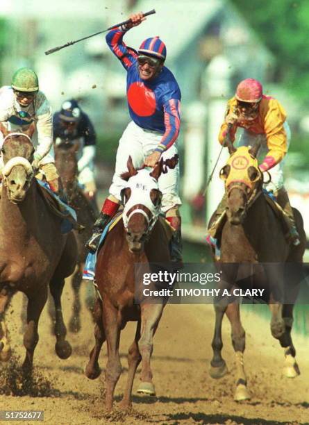 Jockey Gary Stevens celebrates atop Thunder Gulch 6 May after winning the Kentucky Derby in Louisville, Kentucky. At left is third place Pat Day atop...