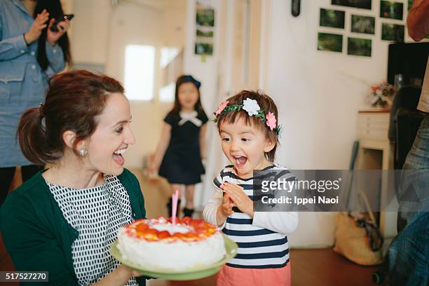 Toddler happily excited by blowing out candles on birthday cake