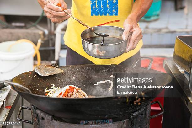 hands of the senior man cooking kway teow noodles at the street market, penang, malaysia - char kway teow stock pictures, royalty-free photos & images