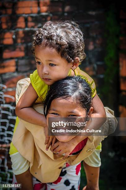 a khmer girl carry her sister on her back - khmer stock pictures, royalty-free photos & images