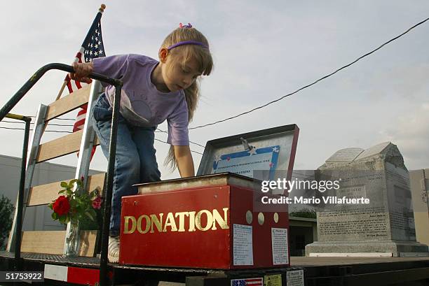 Katie Comer places a dollar bill in a donation box atop a flatbed truck displaying the granite Ten Commandments monument that was removed in 2003...