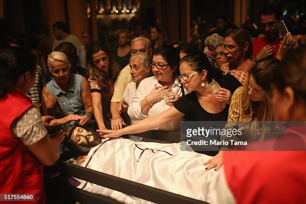 Faithful gather to touch a statue of Jesus in the Nossa Senhora da Paz church following a Good Friday procession during Semana Santa festivities on...