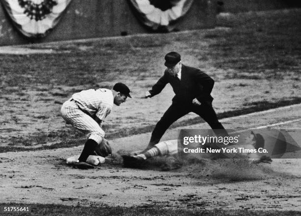 American professional baseball player Stan Musial, a rookie for the St. Louis Cardinals, slides into third base and is called safe by the umpire...