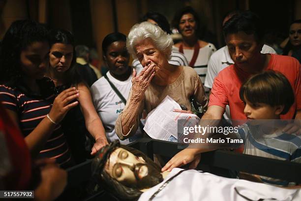 Faithful gather to kiss and touch a statue of Jesus in the Nossa Senhora da Paz church following a Good Friday procession during Semana Santa...