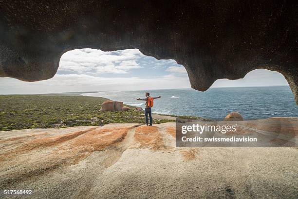 cheerful young man arms outstretched at the remarkable rocks-australia - kangaroo island stock pictures, royalty-free photos & images