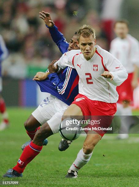 Tomasz Rzasa of Poland is tackled by Sidney Govou of France during the international friendly match between France and Poland at the Stade de France...