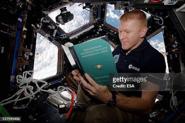 In this handout image supplied by the European Space Agency , ESA astronaut Tim Peake reads a copy of Principia on World Book Day on the...