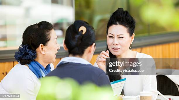 personnes âgées femmes partageant des anecdotes dans un café en plein air - jury loisirs photos et images de collection