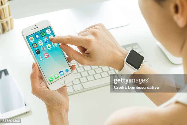 woman holding iphone 6s over the table - app store stock pictures, royalty-free photos & images