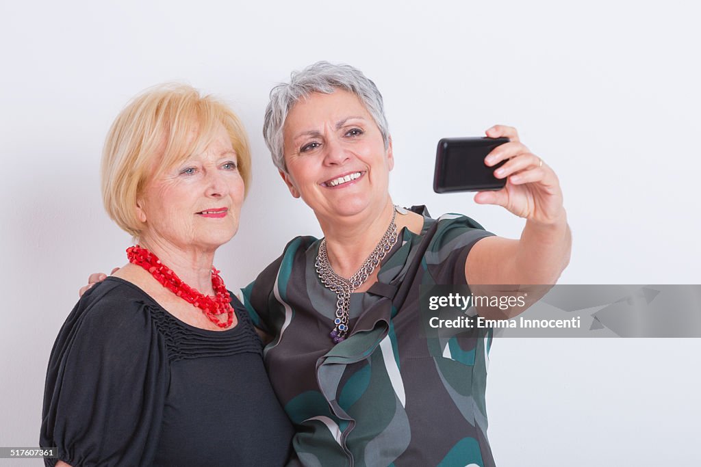 Mature friends taking self photo on phone