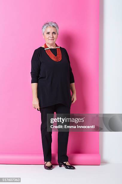 elegant mature woman, studio shot in pink - confidence studio shot foto e immagini stock