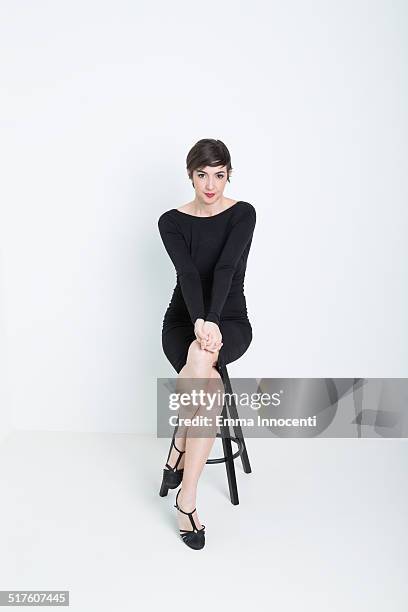 actress sitting on stool - überkreuzte beine stock-fotos und bilder