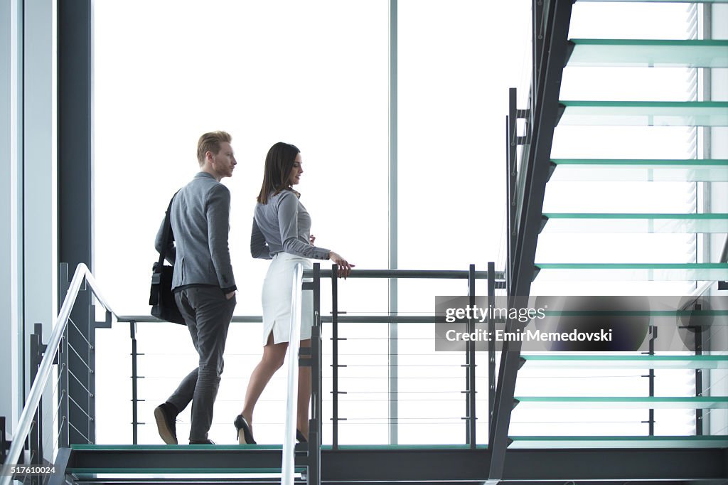 Young businesspeople walking on staircase in hallway.