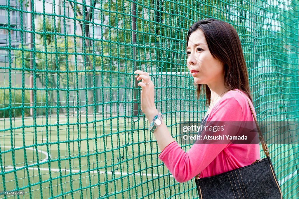 Asian woman looking through fence