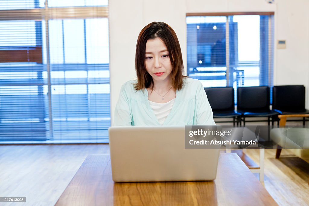 Asian woman using laptop in room