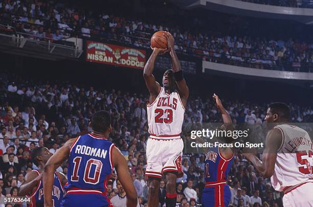 Michael Jordan of the Chicago Bulls jumps to shoot a basket against the Detroit Pistons as Cliff Levingston of the Bulls, Dennis Rodman of the...